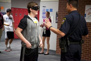 Dec. 19, On-campus school officer Ricky Jimenez explains to junior Kyle Ash how wearing the fatal vision googles impairs your vision and how standardized field sobriety test works in science teacher Susan Shepperd's forensic science class. Photo by Rowan Khazendar.