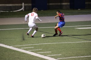 Senior forward Justin Todd maneuvers the ball into position for a cross as a Duncanville defender impedes his path to the goal in Coppell's UIL Regional Quarterfinal match against the Panthers on Apr. 8. The Cowboys will face Flower Mound Marcus in the Region I final match on Saturday afternoon at 2 p.m.  Photo by Shannon Wilkinson.
