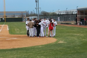 Freshman Shane Steiger hugs Mona Logan and senior Tyler Zabojnik puts his arm around CHS sophomore Jordan Logan. The Logan family came out to the Coppell varsity baseball game Tuesday night when the team, coaches, and students came together to honor the life of Jacob Logan. Photo by Mia Ford.