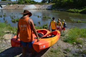 Trinity River Kayak Co. employees A.J. Date and Greg Ludden lead a family down to the river, bringing with them the kayaks the customers will be using. The family spent around three hours kayaking down the Trinity River on Sunday morning. Photo by Sandy Iyer.