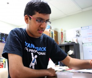 A close up of Kavi Shah smiling and having fun in Mrs. Hunt's room working on a biology experiment. Photo by Mark Slette.