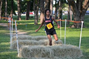 Junior Josh Thomas hurdles over a hay bale at the 29th annual Greenhill School and Luke's Locker Six Mile Relay. Photo by Elizabeth Sims.
