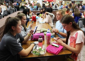 Juniors Caitlin Nutt, Ali Conte and Taylor Abramson take B lunch on Thursday to  catch up on social media while junior Kaylee Geiser attempts to catch up with her friends. Photo by Nicole Messer.