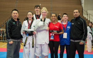 Following the final matches of a day of competition at the 2014 Team Trials in Colorado Springs, three Coppell taekwondo athletes pose with Master Sang Cha (left) after a long day of sparring. New Tech freshman Trinity Sullivan, CHS junior Connor Wilson, CHS sophomore Madison Giddens, taekwondo competitor Kelsey Junious, 8th grader Connor Giddens and Junious's coach Alvaro Mendez (right) come together for a victory group shot. Photo courtesy of Madison Giddens.