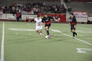 Junior forward Colton Clark dribbles past a Grapevine defender Victor Herrera on Thursday at Mustang-Panther Stadium. The Cowboys, a 3-1 winner over the Mustangs, face Mansfield at 8 p.m. Thursday at Irving Schools Stadium in the class 5A area playoffs. Photo by Shannon Wilkinson.
