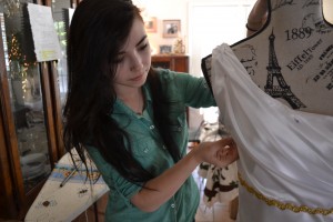 Senior Kenzie Hitz adjusts a pin on her handmade prom dress so she can add last minute stitches. Photo by Elizabeth Sims.