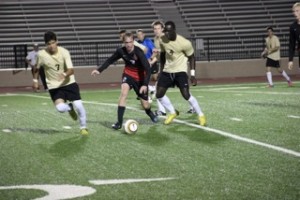 Coppell junior midfielder Drew Brinda dribbles past Mansfield seniors Luis Intriago and Ayo Ogunbire in the Cowboys’ area round match at Irving Schools Stadium on April 3. The Cowboys defeated the Tigers 4-0 and advance to the third round of UIL 5A state playoffs. Photo by Shannon Wilkinson.