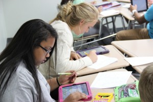 Sophomores Briauna Butler and Lara Collins work together in Mrs. Leyendecker's U.S. history class by using their iPads to help them label an assignment. Photo by Chelsea Banks