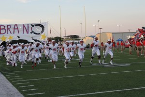 Senior varsity players and former Coppell Youth Football players Parker Wilson, Bryce VonZurmuehlen and Jacob Murray lead the cowboys through the sign at the beginning of the McKinney Boyd game on September 5. Photo by Stephanie Alexander.