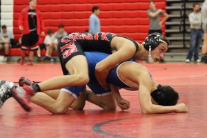 Senior captain Jesse McPherson looks to his coaches for advice while trying to pin his Trinity Christian Academy opponent to the ground. McPherson ended up defeating his opponent on a pin, aiding the Cowboys win against TCA. Photo by Kelly Monaghan.