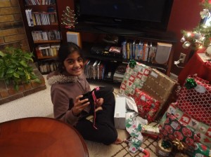 Smrithi Venkatraman, the youngest member of the family, opens her first present of the morning, a new pair of shoes. Photo courtesy of Jyoti Masurekar.