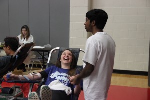 Senior red jacket Ashrith Reddy keeps senior Mackenzie Sork company as she donates blood during the Red Jacket’s second blood drive this year on Feb. 13 in the small gym at Coppell High School. Photo by Sarah VanderPol.