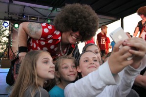 A band member of disco band Le Freak poses for a selfie with Coppell Students in between songs on Friday, May 1st. To celebrate the anniversary of Old Town Coppell's grand opening, a concert and was set up in The Square at at Old Town Coppell. Photo by Amanda Hair.