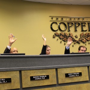 All members of the Coppell City Council raise their hands in approval of the Ordinance of the City of Coppell to approve the past Fiscal Year. The City Council meeting was held in Coppell City Hall and began at 7:30 p.m. Photo by Kelly Monaghan.