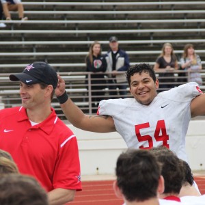 After Coppell beat the Colleyville Heritage Panthers, Coppell High School senior and center Matt Rockfeller throws his hands up in victory as the Cowboys form a huddle after the game on Saturday. The Cowboys claimed a victory over the Panthers with a score of 19-14. Photo by Amanda Hair. 