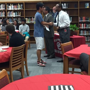 Coppell High School National Merit scholar Beoung Han shakes hands with Coppell ISD Board of Trustee member Anthony Hill on Wednesday in the library. There was 113 students that were nationally recognized for their PSAT scores. Photo by Megan Winkle.  