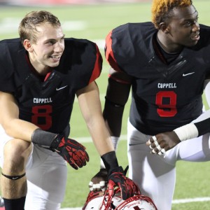Before Friday night’s game, Coppell High School seniors Josh Fink (left) and Aj Johnson (right) wait and applaud their senior teammates for being recognized on senior night at Buddy Echols Field. The game ended with a final score of 44-6, the Coppell Cowboys defeating the Haltom Buffalos. Photo by Amanda Hair.
