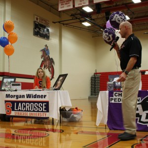 Girls track coach Don Kemp announces Coppell High School  senior Morgan Widner’s signing to Syracuse University for lacrosse in the CHS large gym on Nov.11.  Widner was one of ten girls lacrosse players in the nation to win a scholarship to play the sport. Photo by Kelly Monaghan.