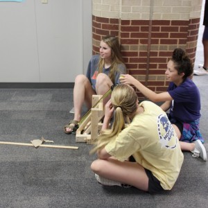 Karl Gscheidle’s physics class tests student made catapults Monday in the main hallway of Coppell High School. Juniors Sarah Houchin, Rachel Kruise and Katie Herklotz sit in the hall to run their trials on the experiment. Photo By Chelsea Banks. 