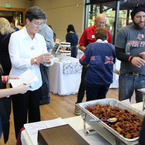 Coppell Mayor Karen Hunt tastes the spicy chicken sample from Wu’s Asian Bistro at the Taste of Coppell on Nov. 8 at the Senior and Community Center. “I don’t know who’s going to win tonight, but it’s going to be neck and neck.” Mayor Hunt said. Photo by Ayoung Jo. 