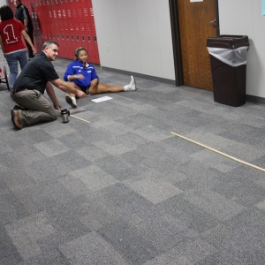Karl Gscheidle’s physics class tests student made catapults Monday in the main hallway of Coppell High School. Junior Lauren Lee and Mr.Gscheidle sit on the receiving end of the catapult to stop the motion of the tennis ball as well as to measure the distance of the ball. Photo By Chelsea Banks.