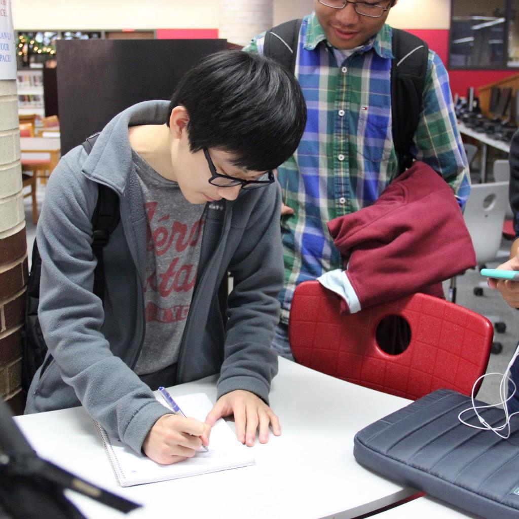 Coppell High School junior Sean Wang signs the attendance sheet for the Coppell Music Chamber Club at the CHS library on Dec. 2. This organization meets every Wednesday at the CHS library. Photo by Jennifer Su. 