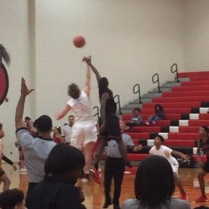 Coppell High School junior small forward Sam Marshall and Trinity High School junior Jareth Roberts tip off Friday night’s home game played in the Coppell High School Large gym. The Cowboys beat the Trojans in a close 49-45 game. Photo by Rachel Buigas-Lopez. 